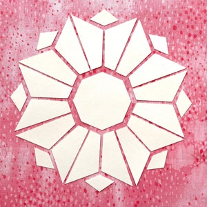 Könnte beinhalten: Weißer Papierauschnitt in einem geometrischen Blumendesign, vor einem rosa Hintergrund mit einem gesprenkelten Muster. Die zentrale Form ist ein Achteck, umgeben von dreieckigen und rautenförmigen Formen.