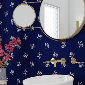 May include: A white porcelain sink with a gold faucet against a blue wall with a white floral pattern. The wall also features two gold mirrors.