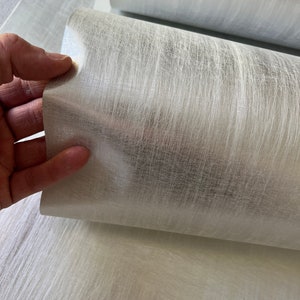 a hand is holding a piece of white fabric