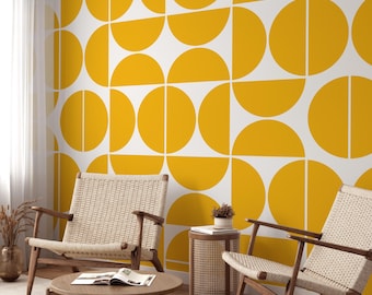 May include: Two wicker chairs with wooden legs and a wooden coffee table in front of a white wall with a geometric pattern of yellow semi-circles.