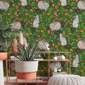 Op de afbeelding: Een groene behang met een herhalend patroon van witte konijnen en rode bessen. De behang is achter een plank met een potplant en een decoratieve voetenbank.