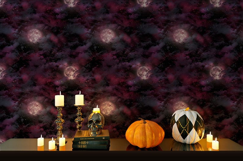 Może przedstawiać: Scena halloweenowa z czarną, białą i złotą dynią, pomarańczową dynią, czaszką i świecami na ciemnym stole przed ciemnym fioletowym i czarnym tłem z białymi księżycami i gwiazdami.