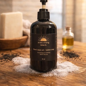 Könnte beinhalten: Eine schwarze Seifenflasche mit Pumpspender, beschriftet mit "everything black". Das Etikett lautet "black seed oil + tallow soap", "Cleansing & Calming 100% Natural 236 ml". Weitere Artikel sind ein Seifenstück, eine kleine Flasche und Samen.