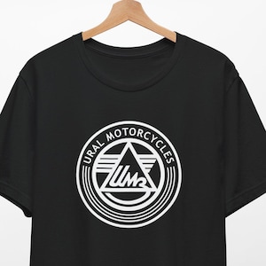 May include: Black t-shirt with a white Ural Motorcycles logo. The logo features a triangle with the letters "UM" inside and the words "URAL MOTORCYCLES" around it.