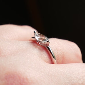 May include: A silver ring with a clear marquise-shaped gemstone.