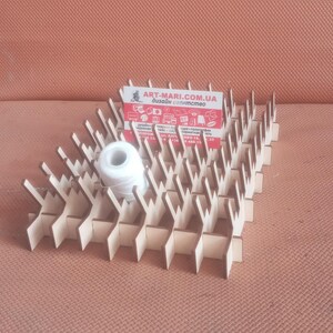 May include: A wooden thread organizer with 36 slots for holding spools of thread. The organizer is made of light brown wood and has a natural finish. A white spool of thread is sitting in one of the slots. The organizer is labeled with the website "art-mari.com.ua" and the text "дизайн сверхмсто" in Ukrainian.