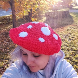 Può includere: Un berretto rosso all'uncinetto con pois bianchi. Il berretto è indossato da una persona con i capelli argentati.