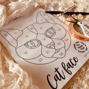 May include: A black and white printable template for a stained glass cat face. The template is numbered 1 through 28, with each number representing a different piece of glass. The template is on a white background.