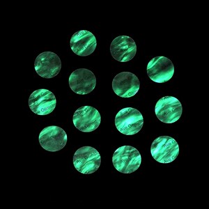May include: A collection of 13 green and black round stickers with the text "Ave Gemstones" on them.