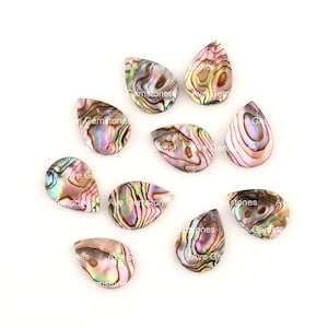 May include: Ten teardrop-shaped abalone shell cabochons with iridescent colours. The shells have a natural, swirling pattern in shades of green, pink, and gold. Some shells have the text "Ave Gemstones" visible on them.
