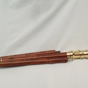 May include: A wooden walking stick with a brass handle. The stick is collapsed into three sections.