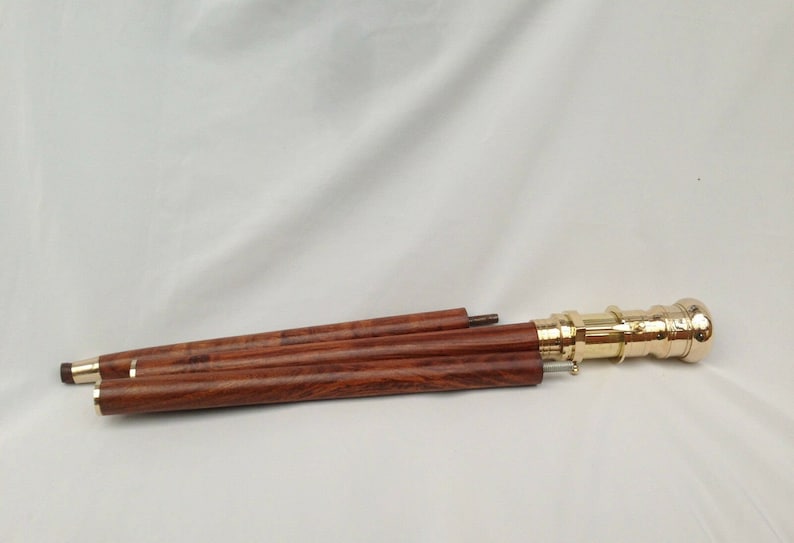 May include: A wooden walking stick with a brass handle. The stick is collapsed into three sections.