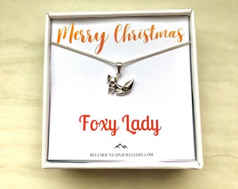 May include: A white gift box with a silver necklace featuring a fox pendant. The box has a white card inside with the text "Merry Christmas" and "Foxy Lady" with the website "bluemountainjewellery.com" printed below.