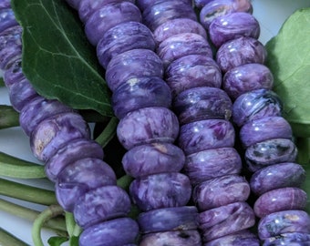 May include: A strand of purple and white gemstone beads. The beads are round and have a smooth, polished finish. The beads are strung on a clear thread.