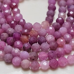 Peut inclure: Gros plan sur plusieurs brins de perles rondes à facettes dans des tons de rose et de violet. Les perles ont un aspect poli, semblable à celui d'une gemme, avec la lumière qui se reflète sur leurs nombreuses facettes. Les perles sont enfilées ensemble.