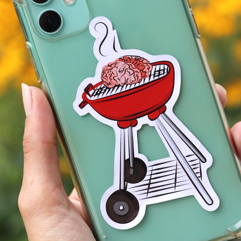 May include: A red and silver grill with a brain-shaped food item inside. The grill has a handle and legs. The image is a sticker on a phone case.