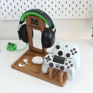May include: A wooden gaming console stand with a headset holder, two controller slots, and a small tray for earbuds. The stand is personalised with the name "Michael Martinez".