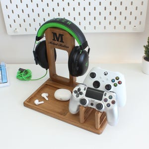 Peut inclure: Un support de jeu en bois avec un casque noir et vert, deux manettes blanches et une station de recharge pour écouteurs. Le support est gravé de la lettre "M" et du nom "Michael Martinez". Idéal pour les joueurs.