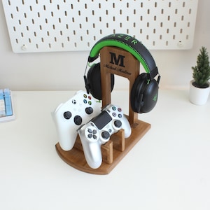 May include: A wooden stand with a green and black headset, two video game controllers, and a personalised nameplate that reads "M Michael Madlines".