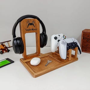 May include: A wooden gaming station with a headphone stand, controller holders, and a tray for accessories. The stand features the text "SuperNova" and a controller graphic. Includes a white mouse and a key. Two game controllers are displayed.