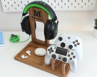Pode incluir: Um suporte de console de jogos de madeira com um suporte para fones de ouvido, dois slots para controladores e um pequeno compartimento para fones de ouvido. O suporte é personalizado com o nome "Michael Martinez".