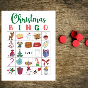 May include: A printable Christmas Bingo card with 25 squares featuring various Christmas-themed images, including a reindeer, a snowman, a gingerbread man, a Christmas tree, a stocking, a candy cane, a gift box, and a penguin. The card is printed on white paper and has a red and green border.