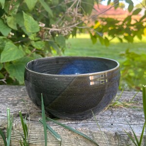 May include: A dark blue ceramic bowl with a black glaze and a thin band of gold paint around the rim.