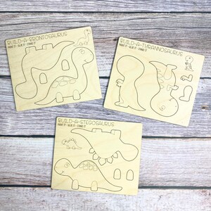 May include: Three wooden dinosaur craft kits, each with a different dinosaur: Brontosaurus, Tyrannosaurus, and Stegosaurus. Each kit includes multiple pieces to assemble the dinosaur, with instructions to paint, glue, and stand the finished product.