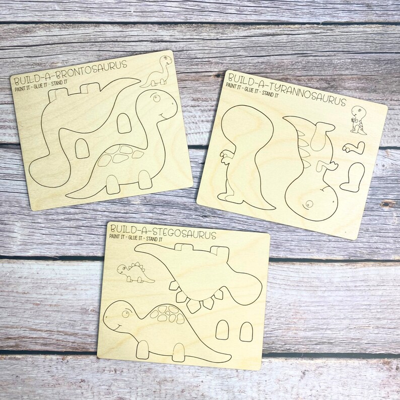 May include: Three wooden dinosaur craft kits, each with a different dinosaur: Brontosaurus, Tyrannosaurus, and Stegosaurus. Each kit includes multiple pieces to assemble the dinosaur, with instructions to paint, glue, and stand the finished product.