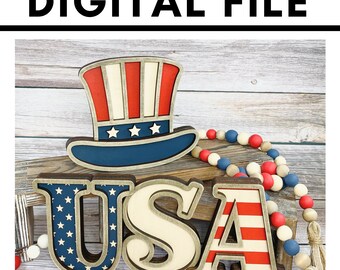 May include: Patriotic wooden decorations spelling "USA" with a red, white, and blue Uncle Sam hat. The letters are in red, white, and blue. A wooden bead garland in red, white, and blue is also present. The text "DIGITAL FILE" is at the top.