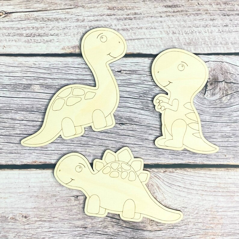 May include: Three unfinished wooden dinosaur shapes, ready to be painted. The dinosaurs are a brachiosaurus, a stegosaurus, and a tyrannosaurus rex.
