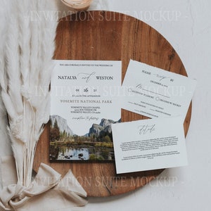 May include: A wedding invitation suite mockup, including a wooden board, a lit candle, and invitation cards. The main card shows the names Natalya and Weston, the date, and a landscape. Other cards feature RSVP details and further information.