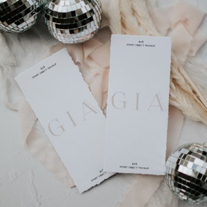 May include: Two white cards with the text "GIA" and "4x9 SMART OBJECT MOCKUP" on them. The cards are surrounded by white and pink fabric, disco balls, and dried pampas grass.