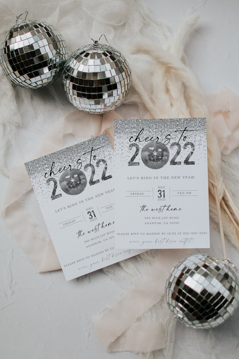 May include: A silver glitter New Year's Eve party invitation with the text "cheer's to 2022" and a disco ball graphic. The invitation includes the date, time, and location of the party. The text "Let's ring in the new year!" is also included.