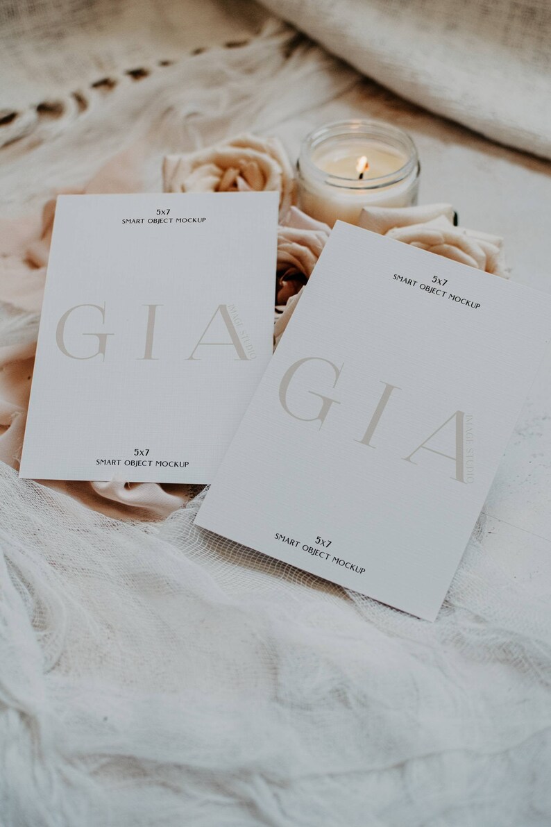 May include: Two white cards with the text "GIA" in a serif font. The cards are on a white fabric background with a lit candle and flowers.