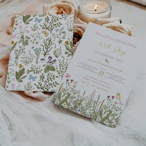 May include: A floral-themed invitation for a first birthday party. The invitation features a watercolor illustration of wildflowers and butterflies. The text on the invitation reads "Our little wildflower Willa Grey is turning one! Please celebrate with us on Saturday, November 28, 2020, at three PM. 24 Dandelion Drive, Boone, North Carolina."