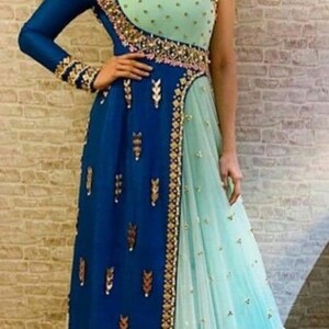 May include: A two-tone formal gown in shades of blue and mint green. The dress features intricate gold embroidery along the neckline, waist, and hem. The bodice is mint green with gold embellishments, and the skirt is a flowing design.