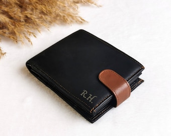 May include: A black leather wallet with a brown leather flap and the initials "R.H." embossed on the front.