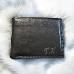 May include: A black leather wallet with the initials "T.K." embossed on the front.