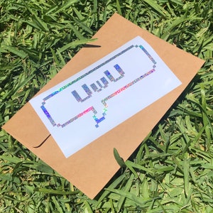 May include: A brown paper envelope with a white sticker featuring a pixelated speech bubble with the word "uwu" inside. The sticker has a holographic finish.