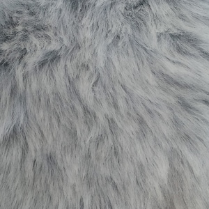 Puede incluir: Primer plano de una tela de piel sintética gris suave y esponjosa. La textura es muy suave y se asemeja a la piel real.