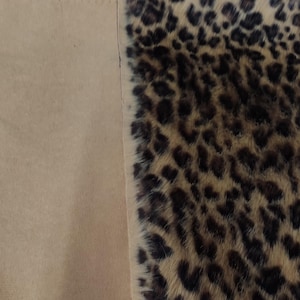 Puede incluir: Primer plano de una tela con estampado de leopardo. El patr&oacute;n presenta manchas marrones oscuras sobre un fondo beige. La tela est&aacute; junto a una tela beige lisa.