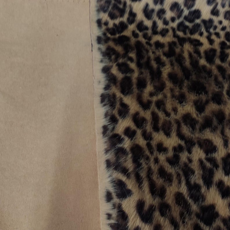 Puede incluir: Primer plano de una tela con estampado de leopardo. El patr&oacute;n presenta manchas marrones oscuras sobre un fondo beige. La tela est&aacute; junto a una tela beige lisa.