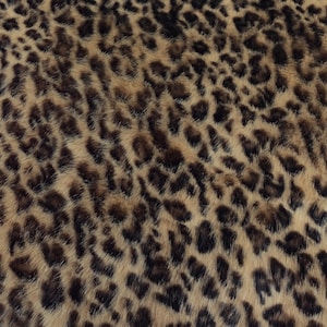 Puede incluir: Primer plano de una tela con estampado de leopardo. El patr&oacute;n presenta manchas marrones oscuras sobre un fondo beige y marr&oacute;n claro. La tela tiene un aspecto suave y texturizado, que se asemeja a la piel de animal.