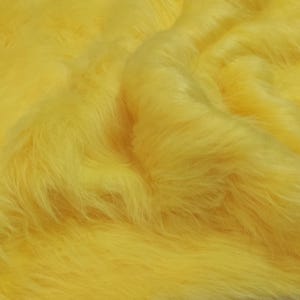 Puede incluir: Primer plano de una tela de piel sintética de color amarillo brillante. La piel es suave y esponjosa, con un ligero brillo.