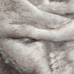 May include: A close-up of a soft, plush, grey faux fur fabric. The fur is long and fluffy, creating a luxurious and cosy texture.