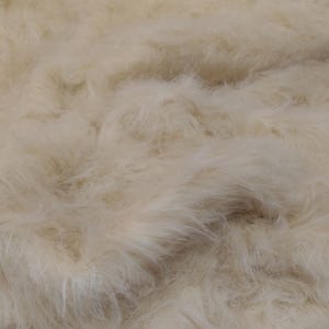 May include: A close-up of a soft, fluffy, white faux fur fabric. The fur is very dense and has a slightly textured appearance.
