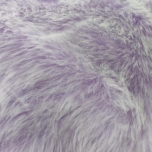 May include: Close-up of a soft, fluffy textile in lavender and white. The material has a shaggy texture, with long, flowing fibres creating a plush appearance. The fabric's colour is a mix of light purple and white.