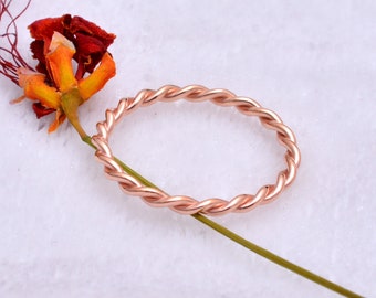 May include: A rose gold twisted band ring. The ring is simple and elegant, with a delicate design.