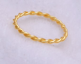 May include: A gold-colored twisted ring. The ring is made of a thin, braided metal.